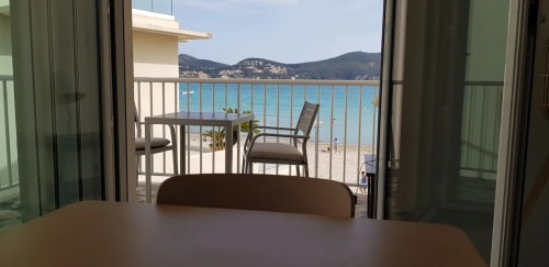 Vue depuis le balcon face à la mer de l'appartement de Saint-Cyr-sur-Mer avec la mer turquoise, les montagnes et le mobilier de plage