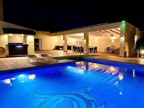 Illuminated private pool at Casa Emilia villa in Moraira with lounge chairs and covered terrace at night