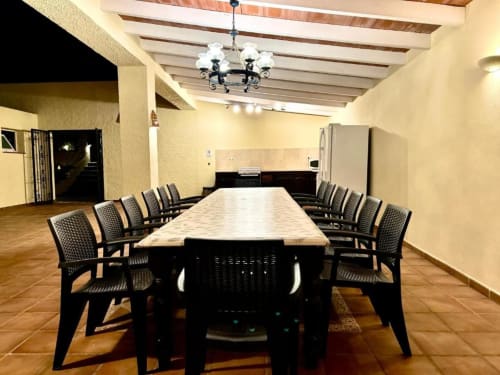 Modern dining room in Casa Emilia villa with long table, black chairs, and chandelier lighting in Moraira