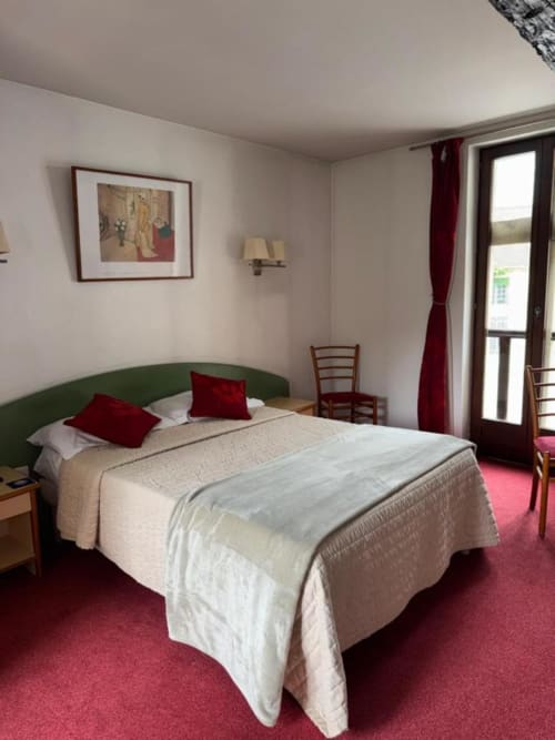 Chambre de l'hôtel Le Château des Saveurs à Mello avec tête de lit verte, accents rouges et moquette rose