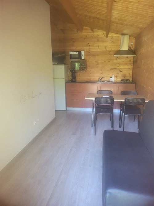 Cozinha de cabana em madeira com área de refeições, micro-ondas, frigorífico e mesa em Casa do Criado Gerês