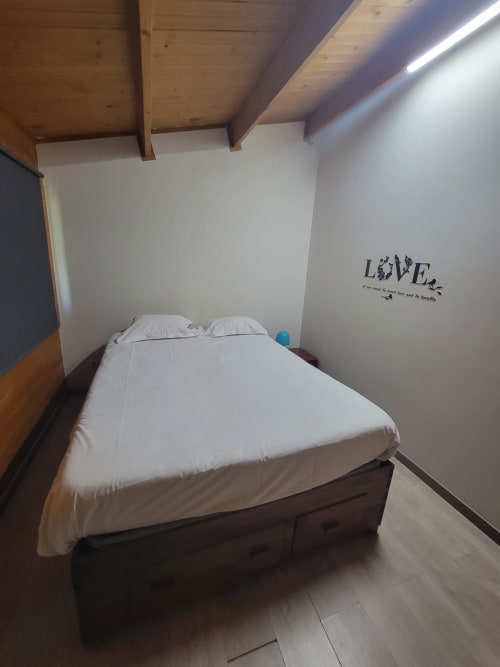 Quarto aconchegante da Casa do Criado Gerês com cama de casal, vigas de madeira no teto e adesivo 'LOVE' na parede em Gerês