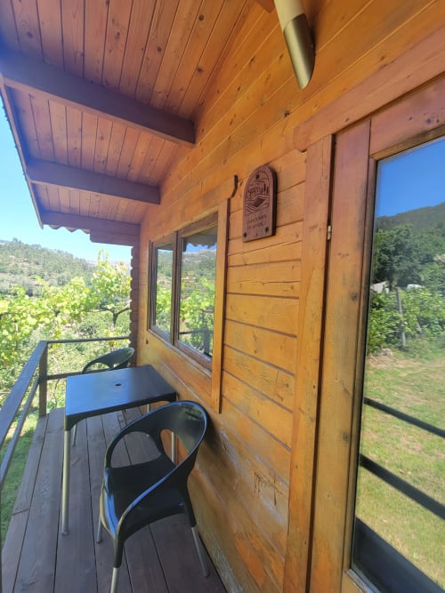 Varanda de cabana em madeira com vistas da montanha na Casa do Criado Gerês, com cadeira preta e decoração rústica