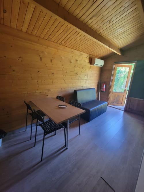 Interior moderno da Casa do Criado Gerês com paredes de madeira, escrivaninha, cadeiras pretas e sofá azul em Gerês, Portugal