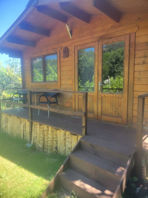 Exterior de cabana de madeira na Casa do Criado Gerês com varanda coberta, janelas voltadas para o jardim e paisagem verde
