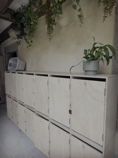 White storage lockers with potted plants and laundry basket at Albergue Santiago de Caminha hostel in Caminha, Portugal