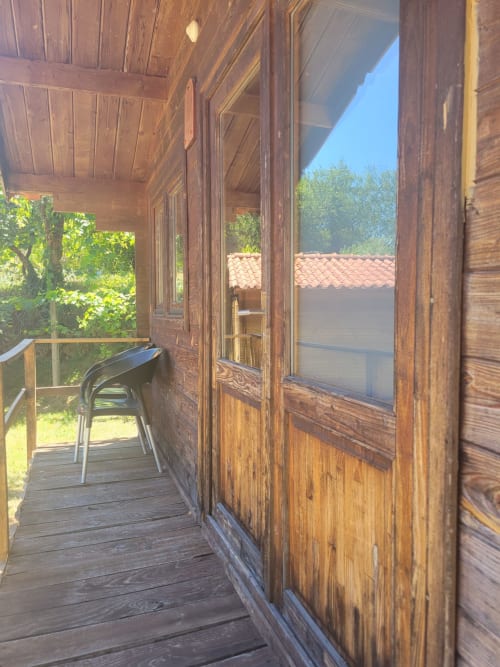 Varanda de cabana em madeira na Casa do Criado Gerês com vista para montanhas, portas rústicas e paisagem campestre