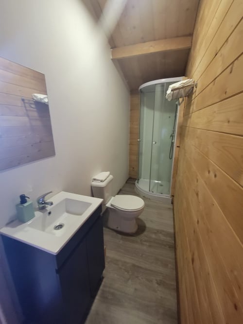 Banheiro moderno na cabana Casa do Criado Gerês com chuveiro, sanitário, pia e detalhes em madeira