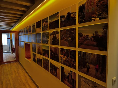 Hostel corridor displaying framed photographs of Caminha landmarks and scenery on yellow walls with wooden flooring at