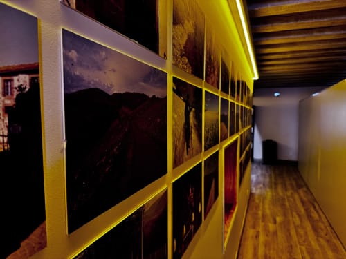 Gallery corridor at Albergue Santiago de Caminha hostel in Caminha, Portugal, featuring illuminated framed photographs on