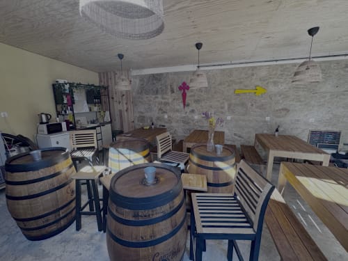 Hostel bar area with wine barrel tables, striped chairs, and pendant lights in Caminha