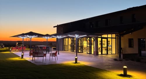 Terrasse de l'hôtel Lieu-dit Boulage à la tombée de la nuit avec parasols illuminés, espaces de détente et architecture contemporaine à Marquefave,