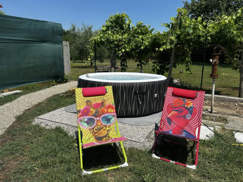 Vasca idromassaggio gonfiabile con lettini colorati nel giardino di Casale Rusignûl, Italia
