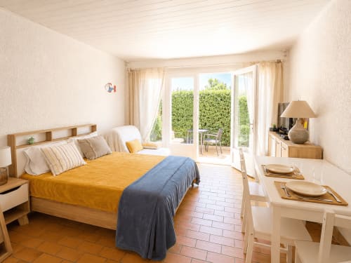 Chambre lumineuse dans l'appartement de Mimizan avec vue sur le jardin, mobilier en bois et accès à la terrasse