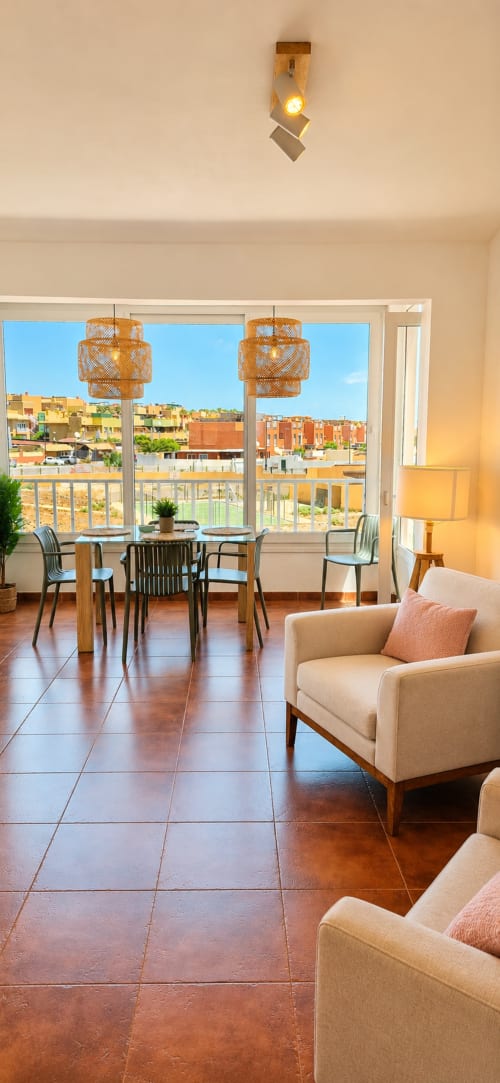 Séjour lumineux avec vue sur l'océan, table à manger, fauteuils beiges, parquet et suspensions tissées