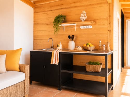 Kitchenette moderne aux murs en bois, mobilier noir et évier dans un appartement de Fuerteventura