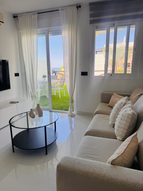 Sala de estar de apartamento frente al mar con vistas al océano, asientos cómodos y acceso a terraza en Rincón de la Victoria