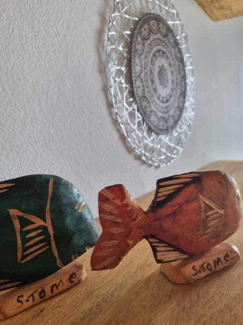 Esculturas decorativas de peixe em madeira e prato com padrões na pousada Casa Amarela, Equador Houses, São Tomé