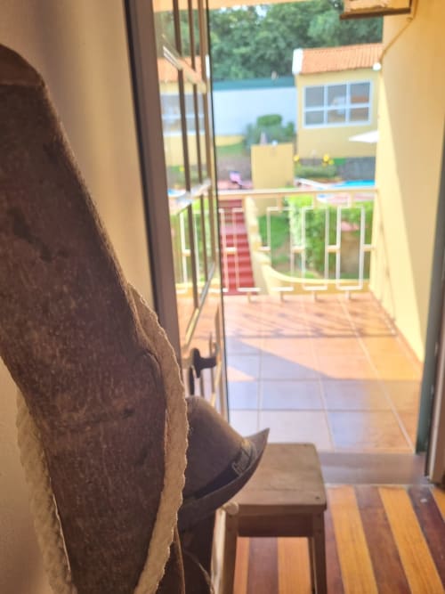 Porta de vidro aberta da casa Casa Amarela em Equador Houses, São Tomé, com vista do jardim, terraço e área de piscina