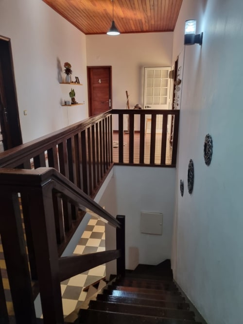 Patamar do segundo andar com corrimãos de madeira e escada na pousada Equador Houses em São Tomé