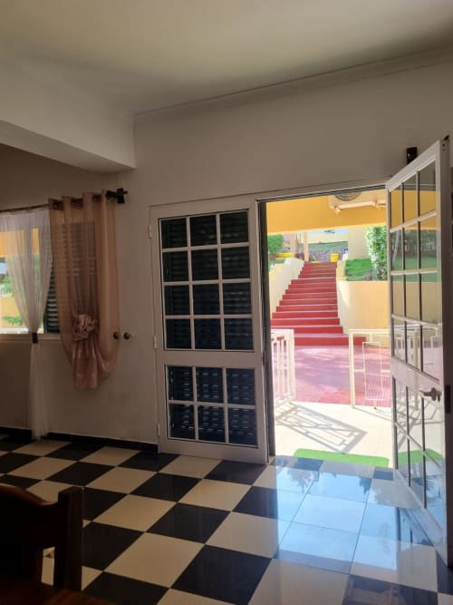 Interior da casa de hóspedes Casa Amarela em Equador Houses, São Tomé, com piso xadrez preto e branco e portas de vidro abertas para