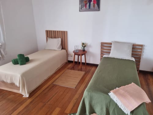 Quarto duplo na pousada Casa Amarela em Ecuador Houses, São Tomé, com camas de madeira e vista para o jardim