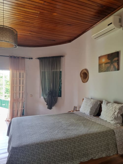 Quarto da Casa Amarela na Equador Houses com teto de madeira, vista do jardim e comodidades modernas em São Tomé
