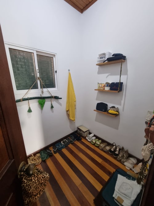 Entrada da pousada Casa Amarela com piso de madeira listrada, prateleiras na parede e armazenamento organizado em Equador Houses, São Tomé