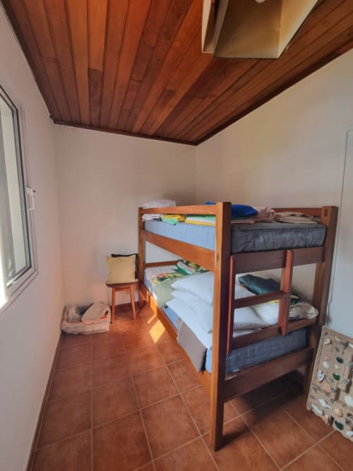 Quarto aconchegante na pousada Casa Amarela em Equador Houses, São Tomé, com camas beliches de madeira e piso em terracota