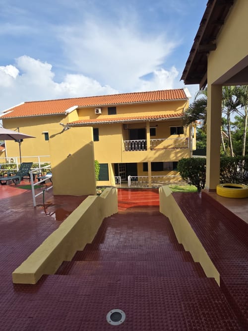 Casa Amarela, chalé da Ecuador Houses em São Tomé com paredes amarelas, telhado de terracota e vista do pátio ajardinado