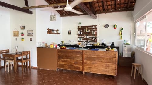 Cozinha da Casa Amarela em Ecuador Houses, São Tomé, com marcenaria em madeira, eletrodomésticos em aço inoxidável e área de refeições