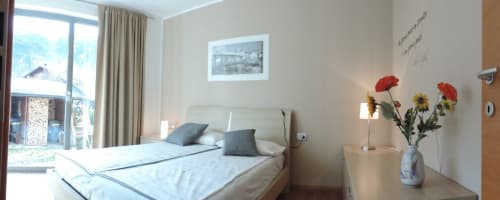 Camera luminosa di B&B Casa Vanzetta con letto matrimoniale, vista giardino, fiori freschi e scenario montano a Ziano di Fiemme