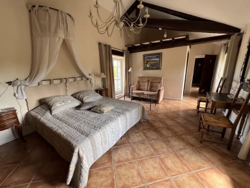 Spacieuse chambre à La Bastide des Princes à Caderousse avec lit à baldaquin, carrelage en terre cuite et coin salon