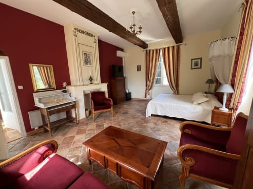 Suite élégante à La Bastide des Princes avec cheminée, accents rouges, poutres en bois et mobilier d'époque