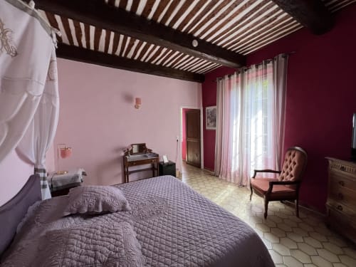 Chambre élégante à La Bastide des Princes à Caderousse avec murs bordeaux, lit queen-size et mobilier classique