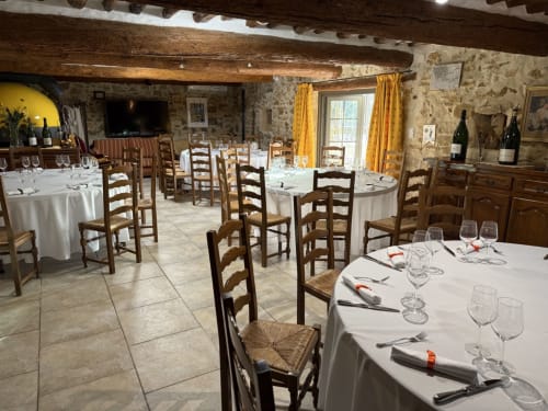 Élégante salle à manger de La Bastide des Princes aux poutres rustiques, murs en pierre et table dressée à Caderousse