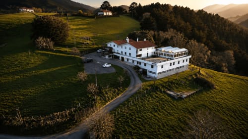 Vista aérea del hotel rural Matzuri Nekazalturismoa en Mutriku, España, rodeado de campos verdes y colinas boscosas