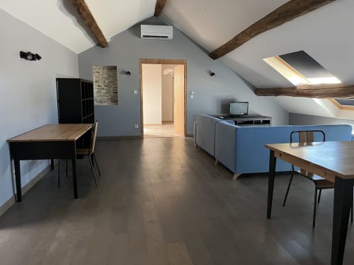 Salon du cottage Mont-Blanc au Saint-Hilaire avec poutres apparentes, tables de salle à manger, canapé bleu et fenêtres de toit