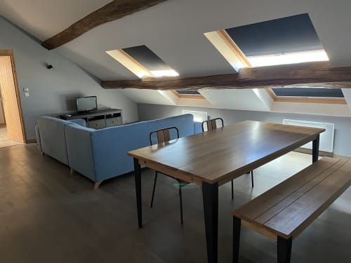 Séjour chaleureux de chalet Mont-Blanc avec table à manger, canapé bleu, lucarne et poutres en bois rustique au