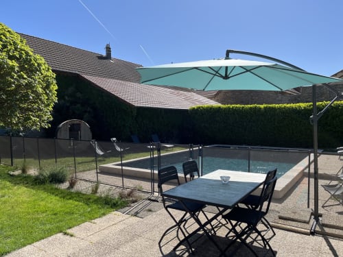 Terrasse au bord de la piscine du gîte Le Saint-Hilaire avec table de repas, parasol vert et piscine privée à Saint-Hilaire-de-Brens.