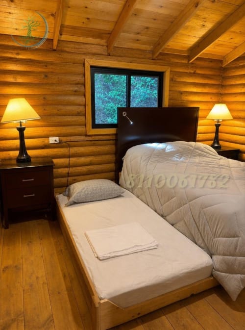 Acogedora habitación de cabaña de troncos en Tierra Cielo & SoLuna con camas gemelas, cabecero oscuro, vigas de madera cálida y vistas a las montañas
