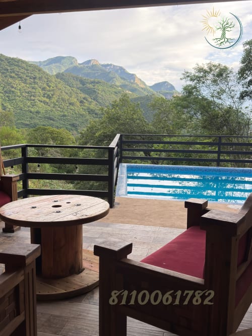 Terraza con vista a la montaña del hotel Tierra Cielo & SoLuna en Potrero de Serna con muebles rústicos de madera y cerco de piscina azul