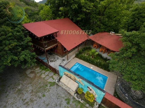 Hotel de montaña Tierra Cielo & SoLuna en Potrero de Serna con lodge de techo rojo, piscina y exuberante bosque