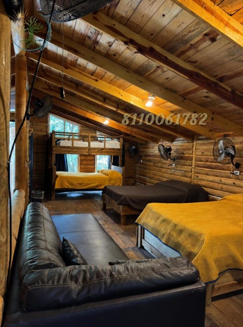 Interior de la cabaña SERRANA en Tierra Cielo & SoLuna con vigas de madera, ropa de cama amarilla, sofá negro y vistas a las montañas