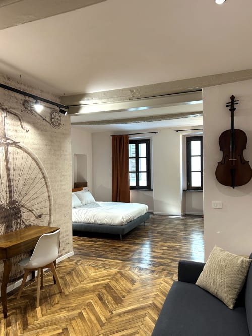 Camera moderna presso Residenza Basiglio a Ceva con arte murale di bicicletta, decorazione di violoncello e pavimento in legno a spina di pesce