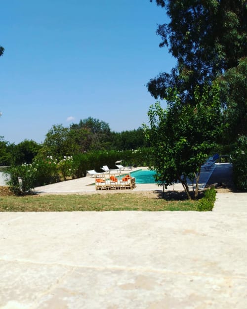Area piscina del Ponteronico Resort con lettini, acqua turchese, spiaggia sabbiosa e alberi rigogliosi sotto cielo sereno
