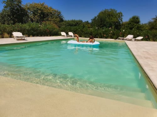 Piscina turchese al Ponteronico Resort di Sessa Aurunca con ospiti su materassini, lettini e alberi