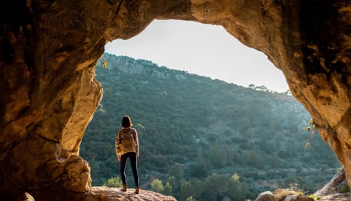 Senderista en cueva con vistas al valle montañoso boscoso de Fuengirola, España