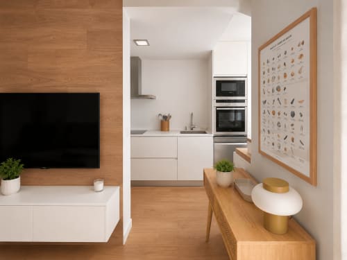 Cocina y salón modernos de planta abierta en Baiona con suelos de madera, muebles blancos y electrodomésticos integrados