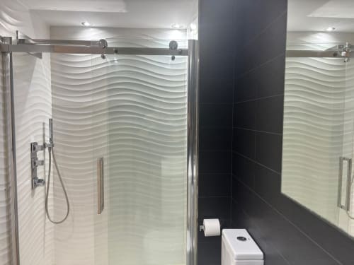 Baño moderno en apartamento Holibai, Baiona con ducha de cristal, azulejos ondulados y accesorios contemporáneos